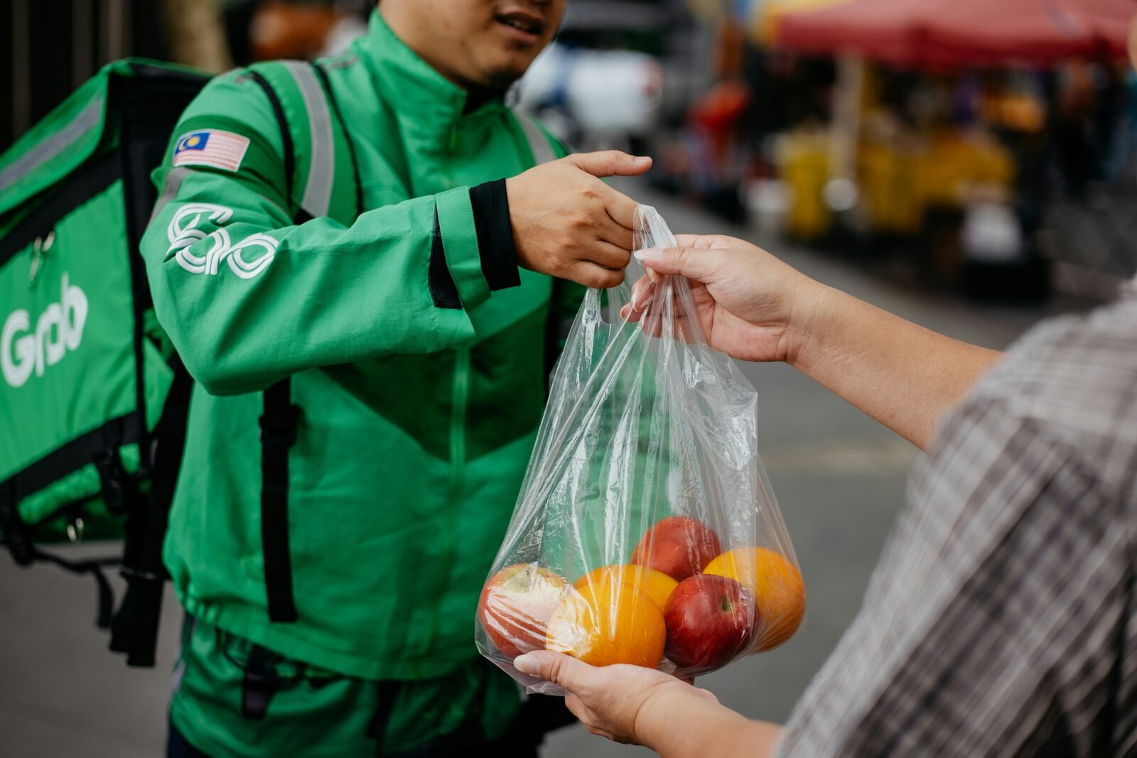 FreshRhythm delivery rider handing over a produce bag
